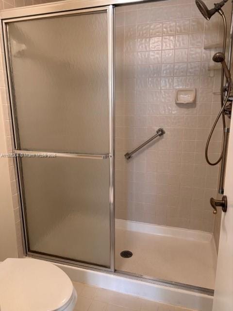 bathroom with tile patterned floors, toilet, and walk in shower