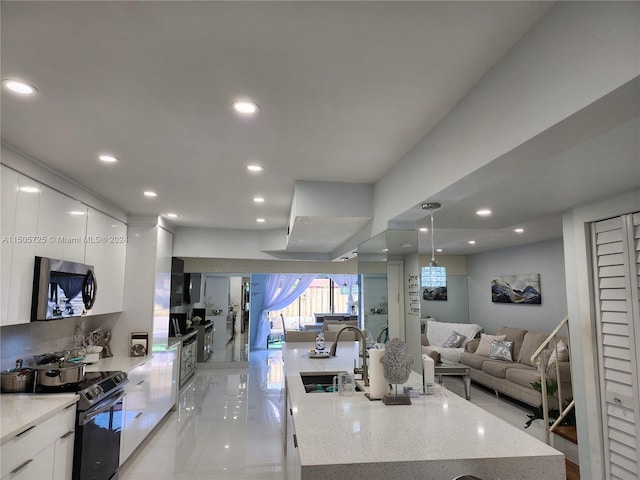 kitchen with stainless steel appliances, white cabinetry, a large island, and light stone counters