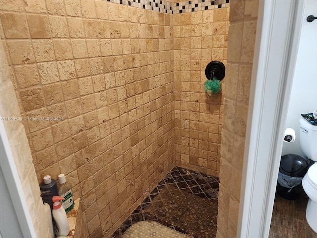 bathroom with tiled shower, hardwood / wood-style flooring, and toilet