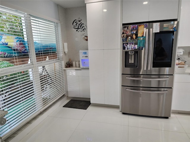 kitchen with stainless steel fridge, white cabinetry, and light tile patterned floors