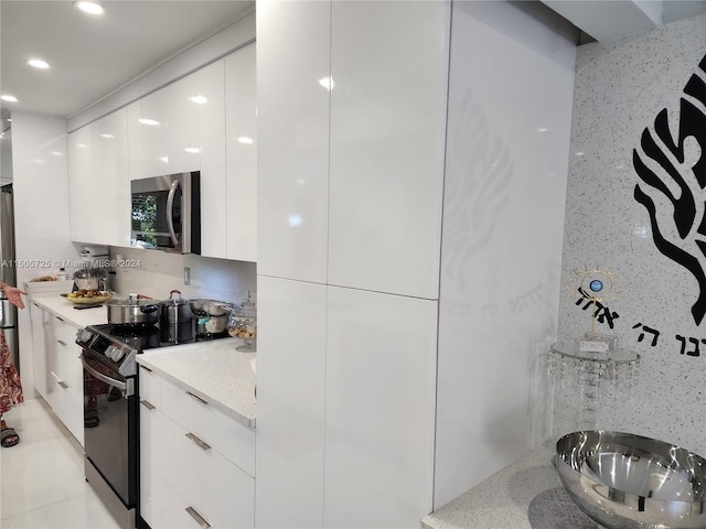 kitchen with backsplash, white cabinets, sink, light stone countertops, and stainless steel appliances