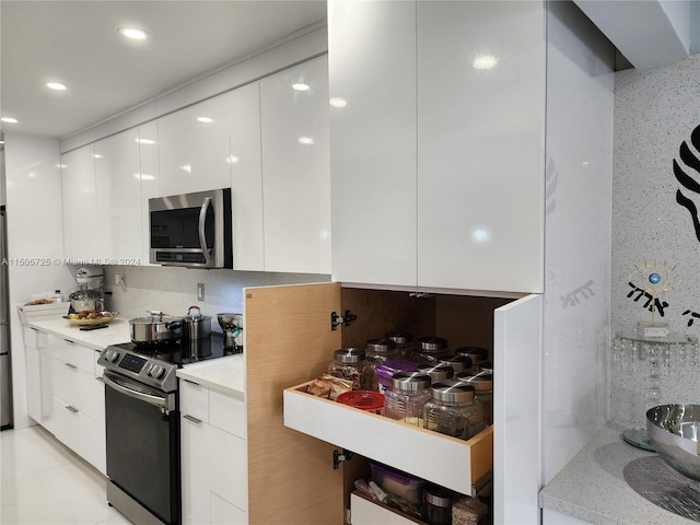 kitchen featuring white cabinets, backsplash, stainless steel appliances, and light tile patterned flooring