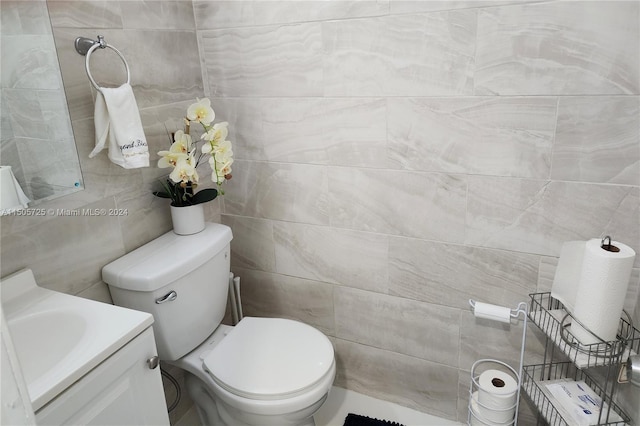 bathroom with vanity, toilet, and tile walls