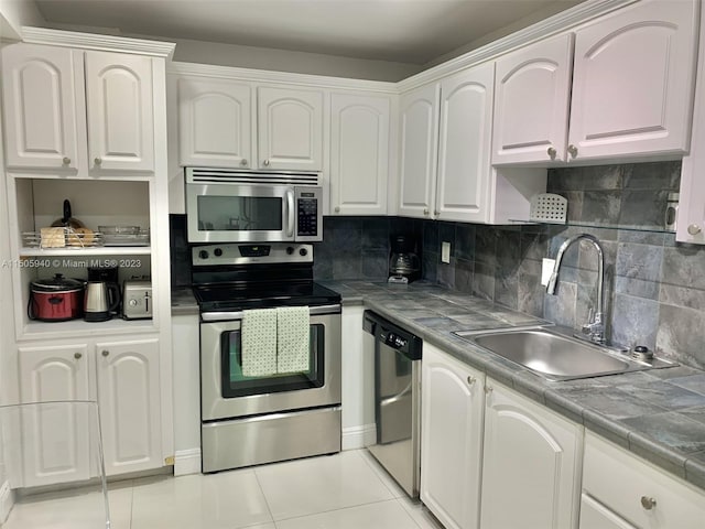 kitchen with light tile patterned flooring, sink, tile countertops, appliances with stainless steel finishes, and white cabinets