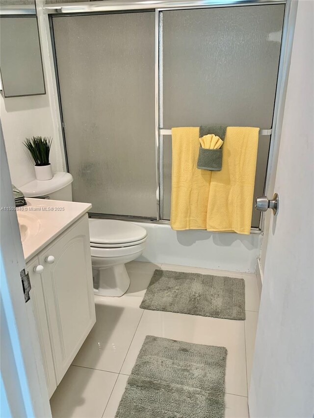 full bathroom with vanity, toilet, tile patterned floors, and bath / shower combo with glass door