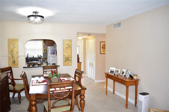 tiled dining room featuring a textured ceiling