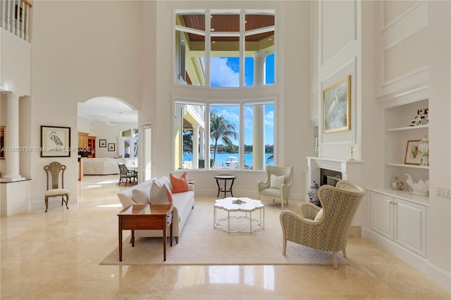 tiled living room with built in shelves, a towering ceiling, and a water view