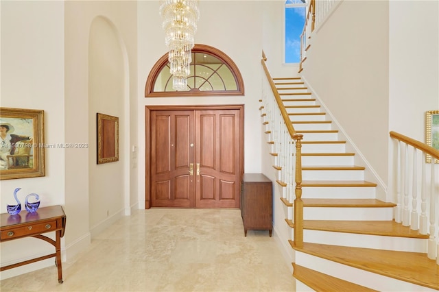 tiled entrance foyer featuring an inviting chandelier and a towering ceiling