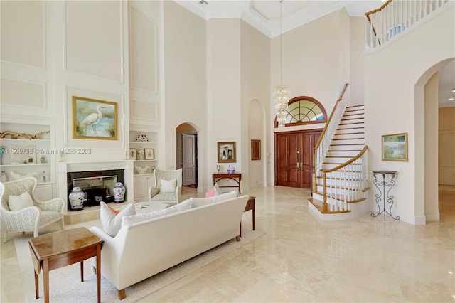 living room with a towering ceiling, ornamental molding, and built in features