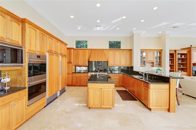 kitchen with built in appliances, ornamental molding, a kitchen breakfast bar, a kitchen island with sink, and decorative backsplash