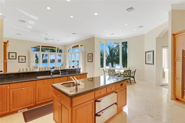 kitchen with a kitchen island with sink, ceiling fan, sink, and light tile floors