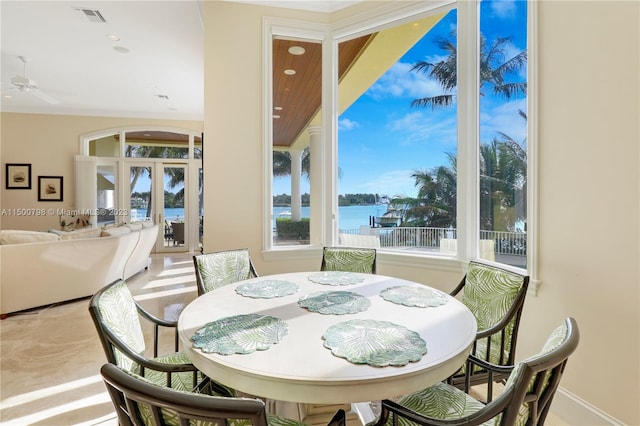 dining room with ceiling fan, a water view, light tile floors, vaulted ceiling, and french doors