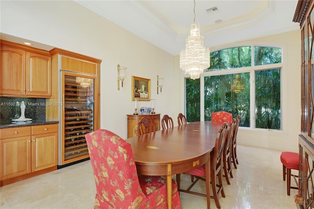 tiled dining room with an inviting chandelier, beverage cooler, plenty of natural light, and a tray ceiling