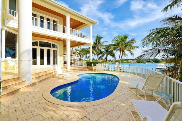 view of swimming pool with a patio area, french doors, and a water view