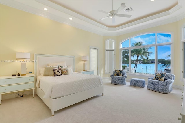 bedroom featuring ceiling fan, crown molding, light carpet, a water view, and a raised ceiling