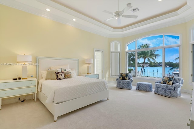 bedroom featuring a water view, light colored carpet, ornamental molding, and a tray ceiling