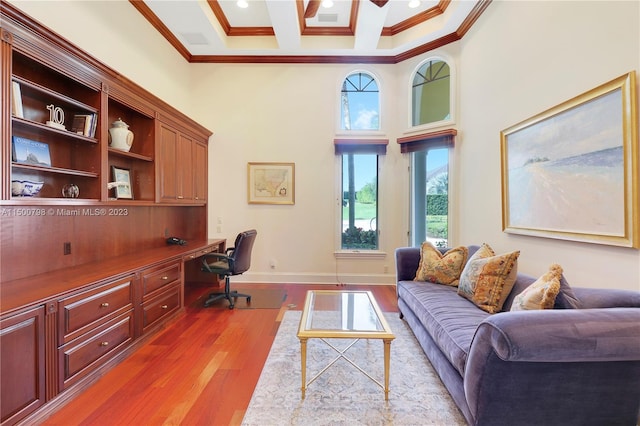 office space featuring a high ceiling, built in desk, light hardwood / wood-style flooring, and crown molding