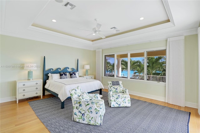 bedroom featuring ceiling fan, crown molding, a raised ceiling, and light hardwood / wood-style flooring