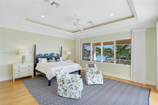 bedroom with a raised ceiling, ornamental molding, and light hardwood / wood-style floors