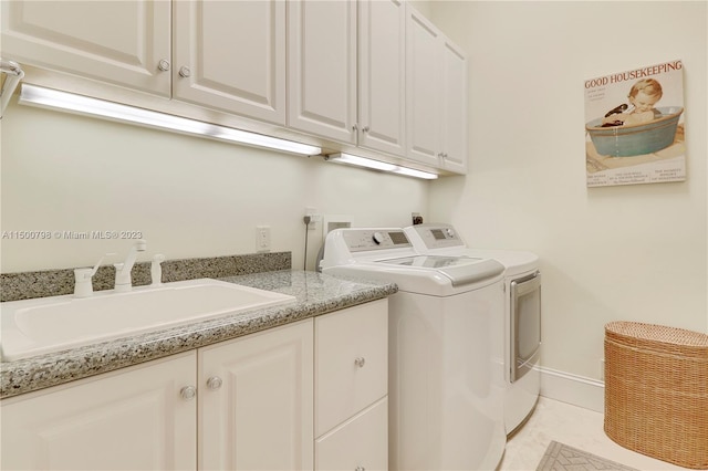 clothes washing area featuring washer and dryer, light tile flooring, cabinets, and sink