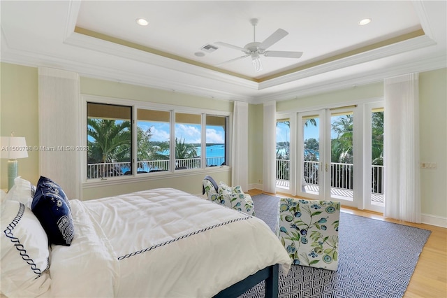 bedroom featuring ceiling fan, a raised ceiling, light hardwood / wood-style flooring, and access to outside