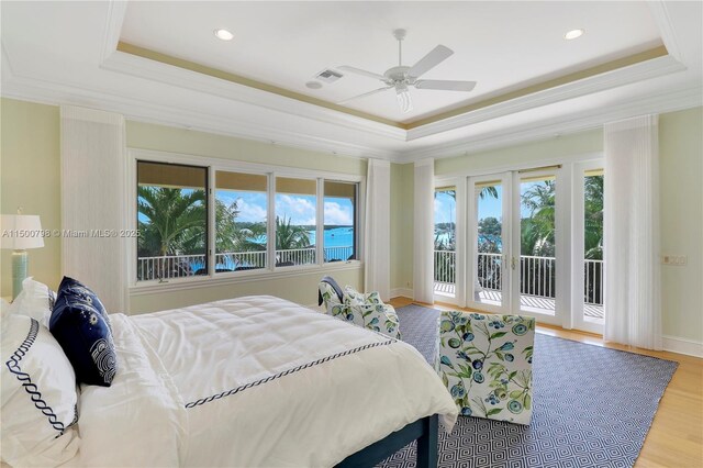 bedroom featuring a raised ceiling, ornamental molding, hardwood / wood-style floors, and access to outside