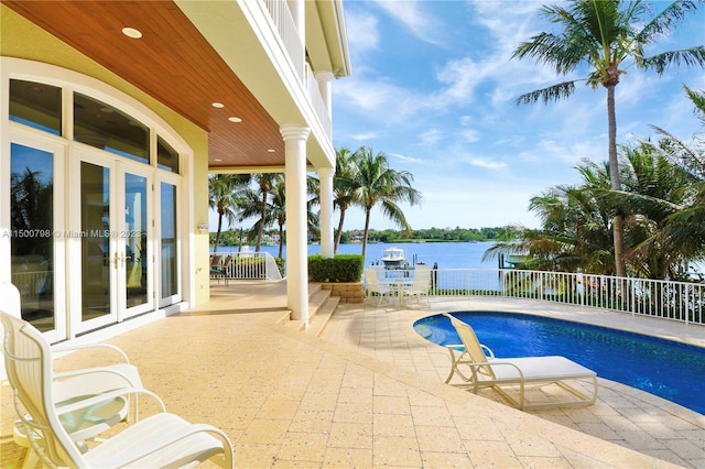 view of pool with french doors, a water view, and a patio area