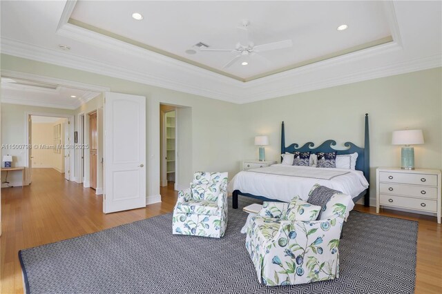 bedroom featuring crown molding, a tray ceiling, and wood-type flooring