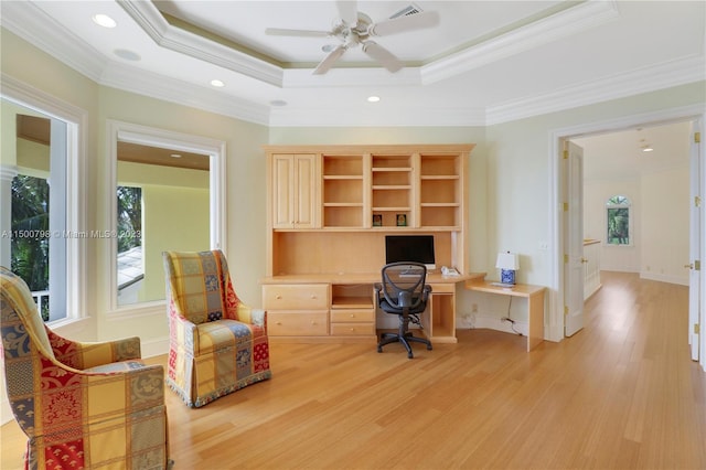 office space with ornamental molding, a tray ceiling, and light wood-type flooring