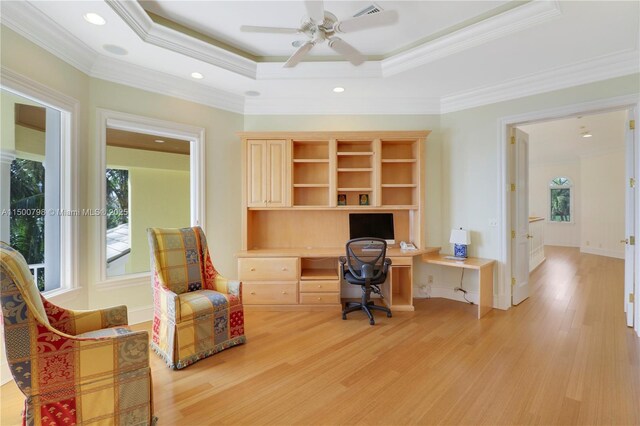 office area with crown molding, built in desk, light wood-type flooring, and a tray ceiling