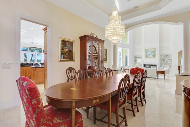 tiled dining space with a raised ceiling, decorative columns, and a notable chandelier