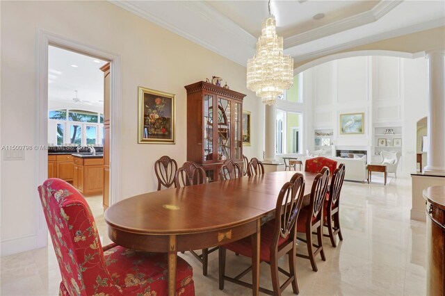 dining room with crown molding, a chandelier, built in shelves, and decorative columns