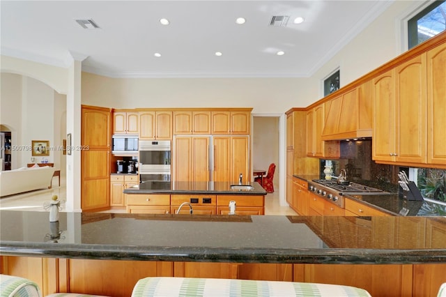 kitchen featuring dark stone counters, crown molding, sink, and stainless steel appliances