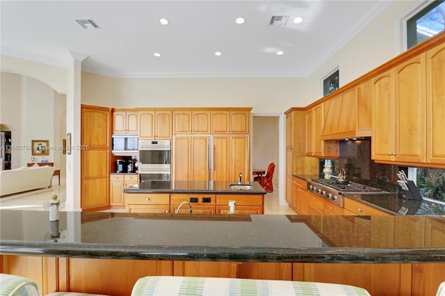 kitchen with tasteful backsplash, custom exhaust hood, built in appliances, kitchen peninsula, and crown molding