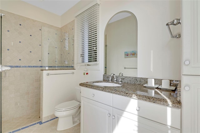 bathroom featuring large vanity, toilet, and tiled shower