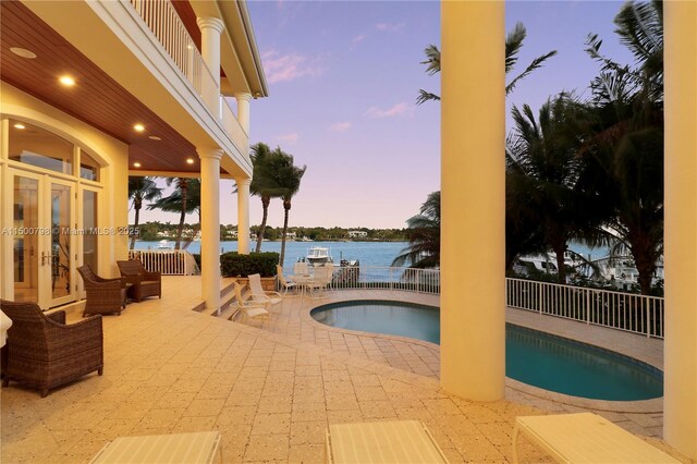 17571 SE Conch Bar Ave, Jupiter, FL 33469 - pool at dusk featuring a water view and a patio