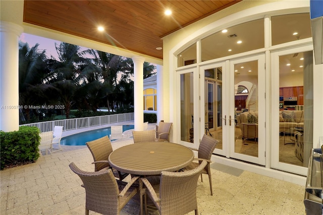 patio terrace at dusk with a fenced in pool and french doors