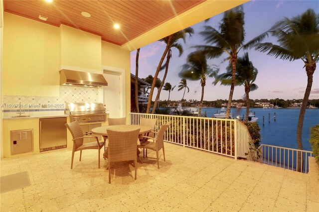 patio terrace at dusk featuring area for grilling, sink, grilling area, and a water view