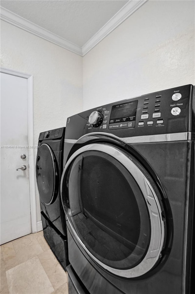 clothes washing area featuring crown molding and washer and clothes dryer