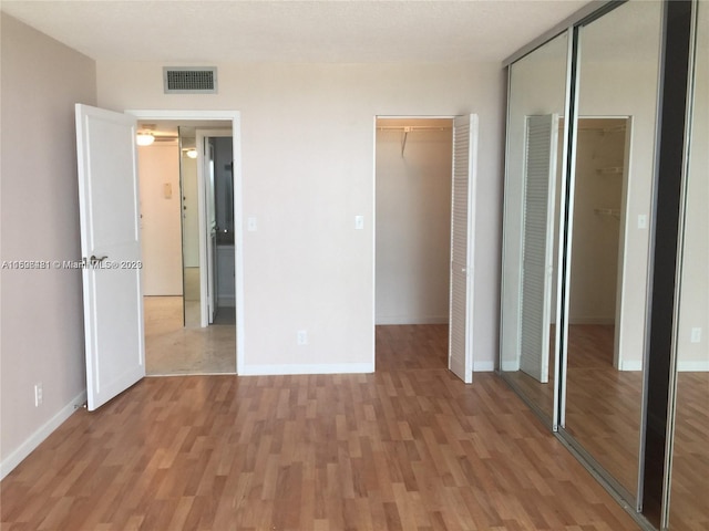 unfurnished bedroom with multiple closets and hardwood / wood-style flooring