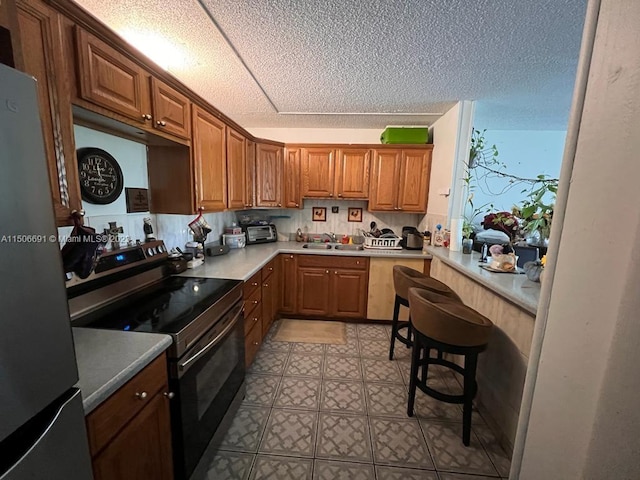 kitchen with sink, a textured ceiling, stainless steel appliances, and a breakfast bar area