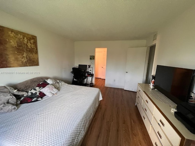 bedroom with a textured ceiling and dark hardwood / wood-style floors