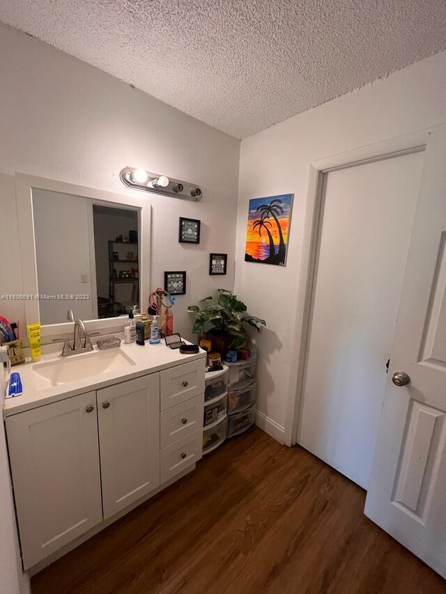 bathroom with hardwood / wood-style flooring, vanity, and a textured ceiling