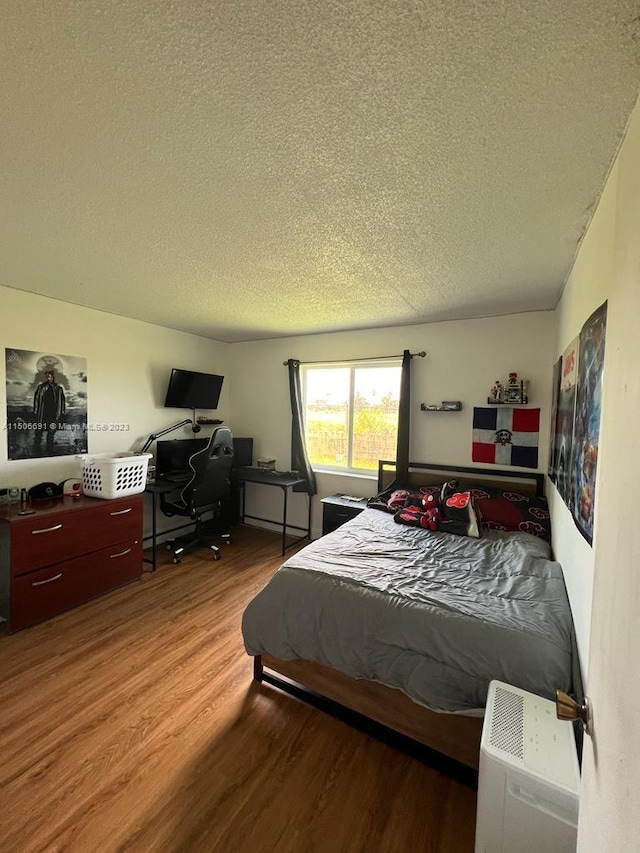 bedroom with a textured ceiling and light wood-type flooring