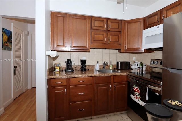 kitchen featuring tasteful backsplash, sink, stone countertops, and appliances with stainless steel finishes