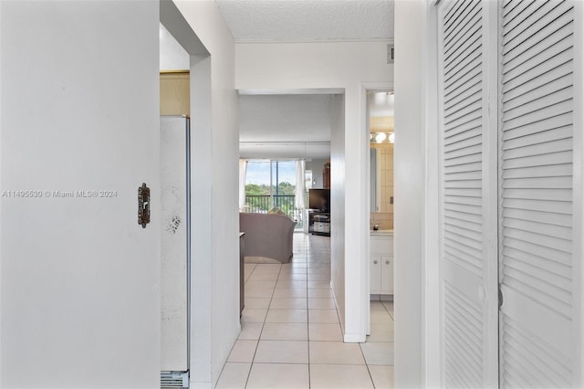 corridor featuring light tile patterned floors and a textured ceiling