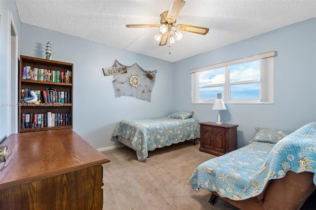 bedroom with ceiling fan, light colored carpet, and a textured ceiling