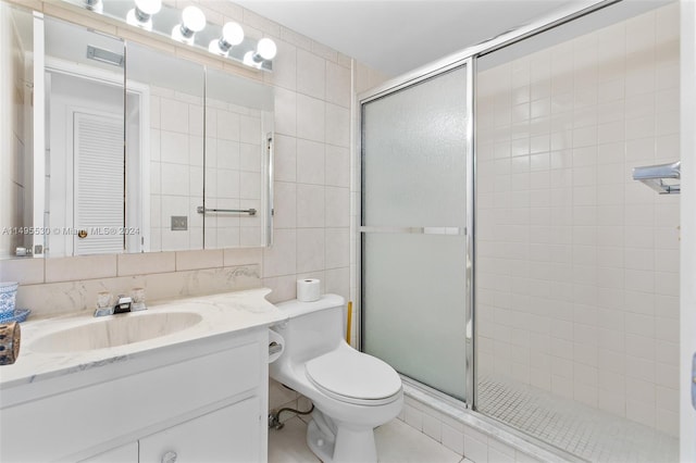 bathroom featuring vanity, toilet, tile walls, and a shower with shower door