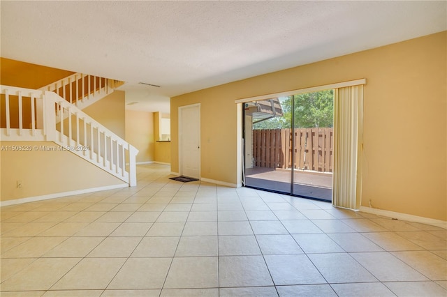 empty room with a textured ceiling and light tile patterned floors