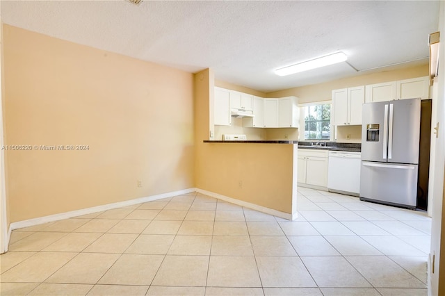 kitchen featuring white cabinetry, a textured ceiling, light tile patterned floors, stainless steel fridge, and white dishwasher